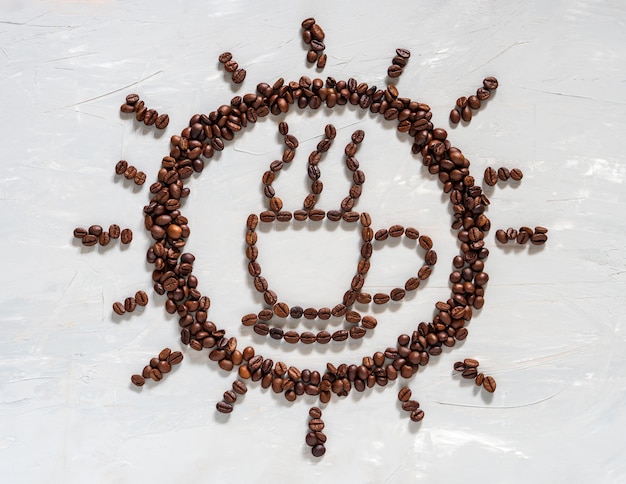 Foto grano de café en forma de copa y sol en piso blanco