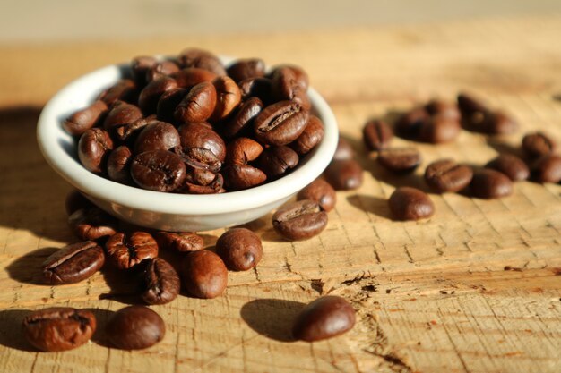 grano de café en un plato blanco en la mesa de madera