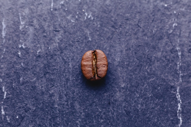 Un grano de café sobre piedra negra.