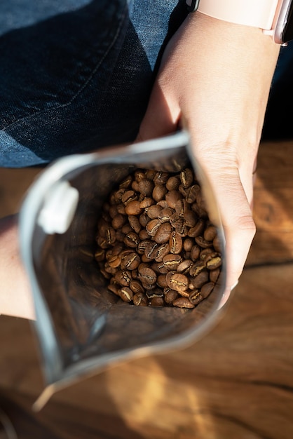 El grano de café tostado se empaqueta en una bolsa que el barista sostiene en sus manos Concepto de preparación de café de vista superior