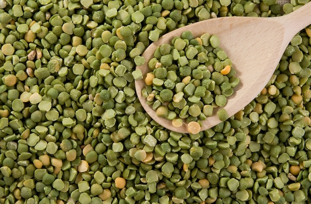 Grano de guisante verde en cuchara de madera