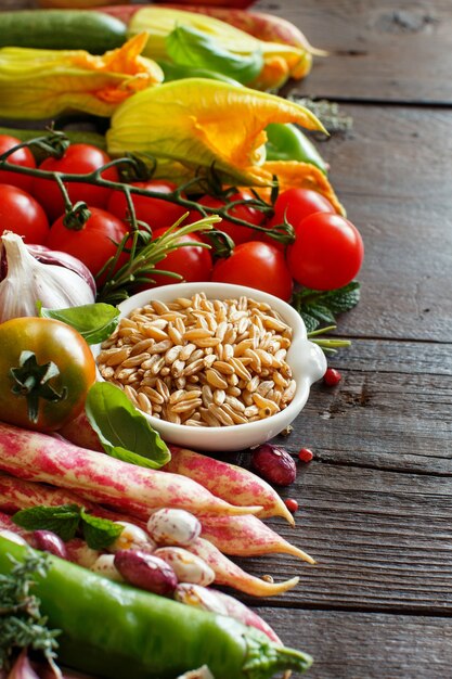 Grano kamut crudo con verduras sobre madera