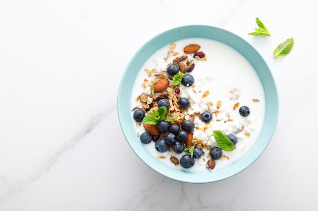 Granola de ar谩ndanos y almendras con reques贸n de yogur griego y vista superior de bayas frescas