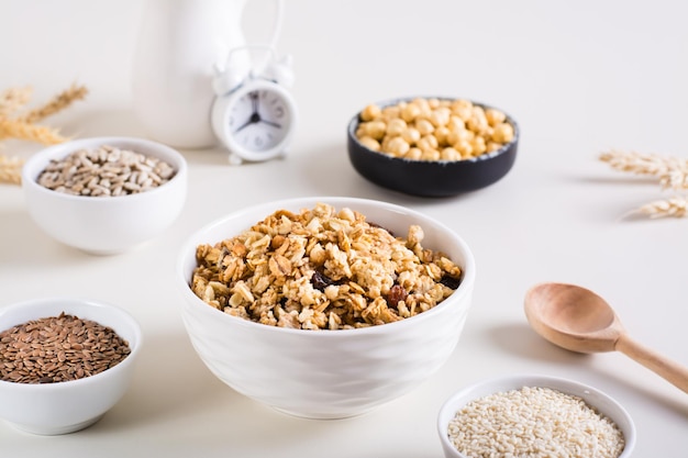 Granola assada em uma tigela e sementes diferentes em tigelas na mesa Café da manhã saudável