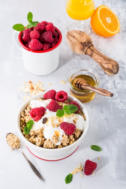 Granola de avena con bayas y yogur sobre fondo gris claro. Concepto de desayuno saludable.