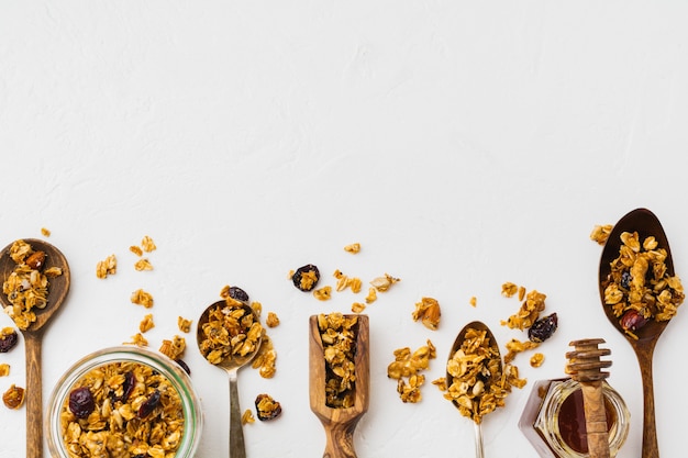 Granola de avena con frutos secos, semillas de chía y girasol, miel en tarro de cristal. Vista superior.