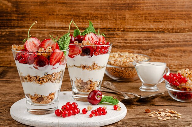 Granola con bayas frescas y yogur sobre fondo de madera, espacio de copia