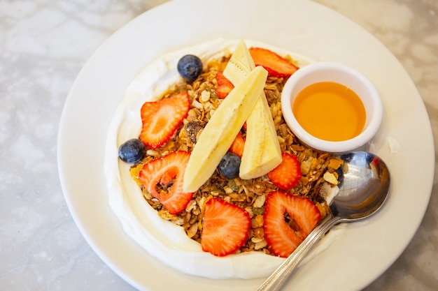 Granola caseira com iogurte e frutas mistas e mel de vista superior.