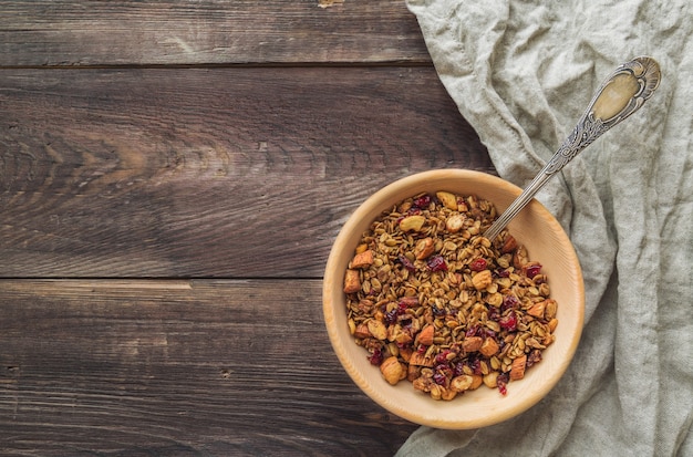 Granola caseira com nozes e cranberries secas em uma tigela de madeira com fundo de madeira rústica