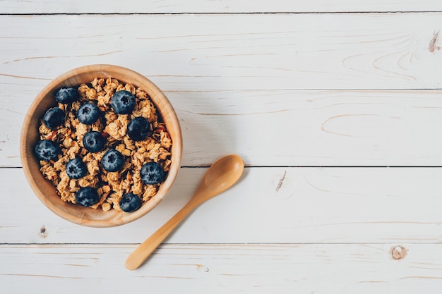 Granola casera y bayas frescas en la mesa de madera con espacio.