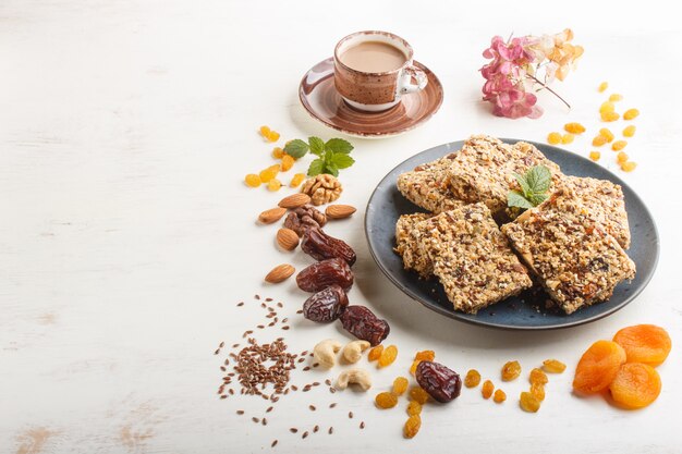 Granola casera de copos de avena, dátiles, albaricoques secos, pasas, nueces en plato de cerámica azul. Vista lateral.