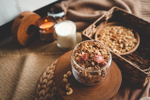 Granola casera en un frasco de vidrio con el trasfondo de velas de leche y decoración concepto de buenos días