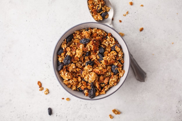 Granola cocido con las pasas en el cuenco, fondo blanco.