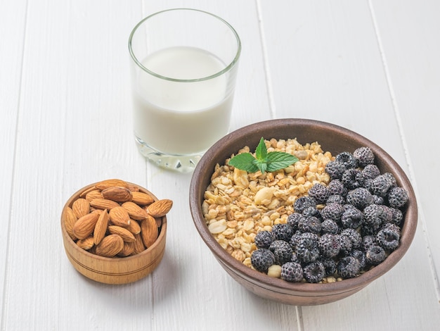 Granola com amêndoas de framboesas pretas e leite em uma mesa branca