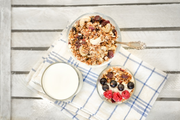 Granola com frutas e nozes, um copo de iogurte em uma toalha branca. Pequeno-almoço americano tradicional