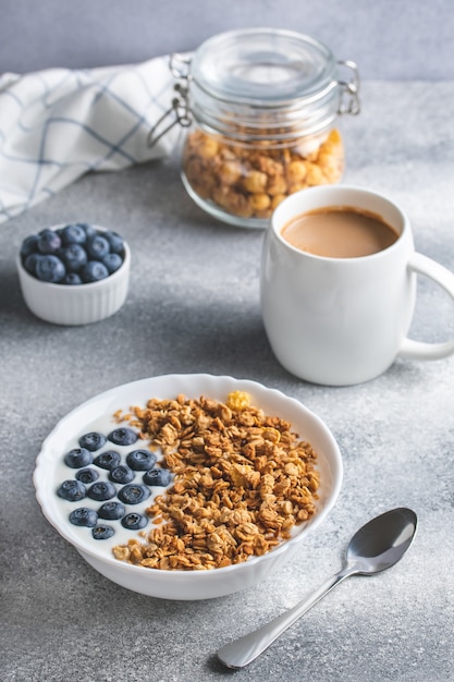 Granola com iogurte e café em uma mesa cinza