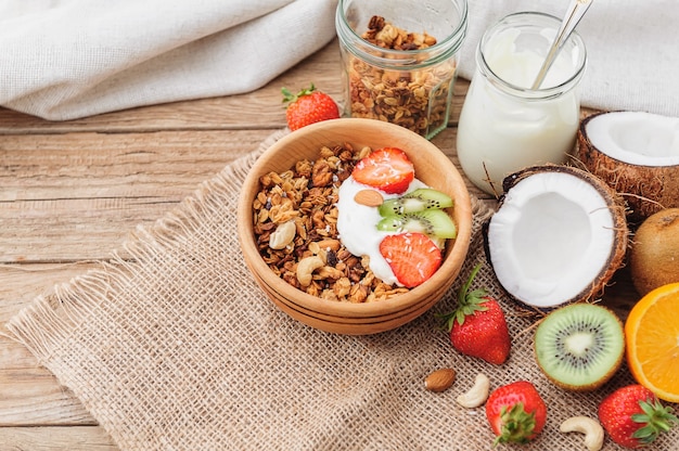 Granola com iogurte grego e frutas em fundo de madeira em estilo rústico