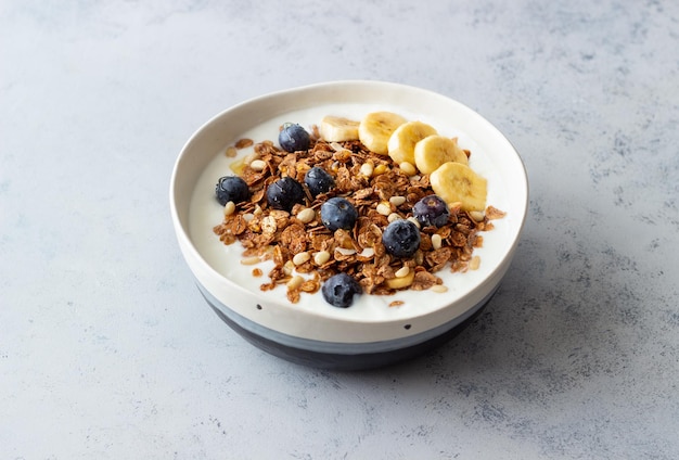 Granola com iogurte, mirtilos, nozes, banana e mel. Muesli. Alimentação saudável. Comida vegetariana.