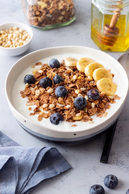 Granola com iogurte, mirtilos, nozes, banana e mel. Muesli. Alimentação saudável. Comida vegetariana.