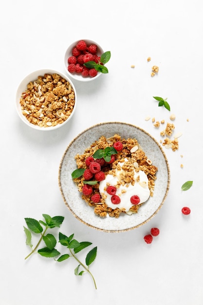 Granola com iogurte natural branco e framboesa fresca em uma tigela de alimentos saudáveis para o café da manhã