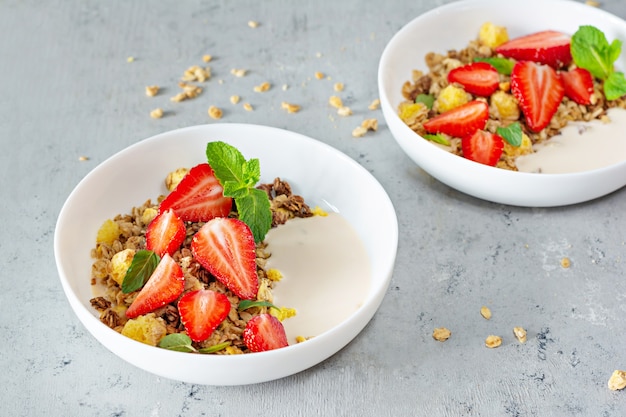 Granola crujiente casera con nueces, frutos secos, fresas frescas, menta y yogur