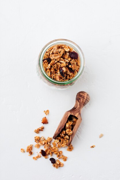 Granola de aveia com frutos secos, sementes de chia e girassol, mel em frasco de vidro. Vista do topo.