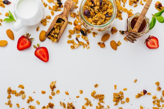 Granola de aveia com frutos secos, sementes de chia e girassol, mel em frasco de vidro. Vista do topo.