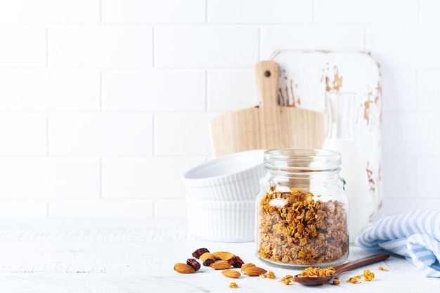 Granola de aveia com nozes e frutas secas para preparar um café da manhã saudável em uma mesa de cozinha bem iluminada. Estilo branco escandinavo. Foco seletivo