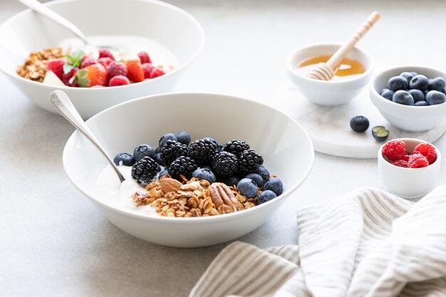 Granola de café da manhã com iogurte e frutas vermelhas em um fundo de concreto