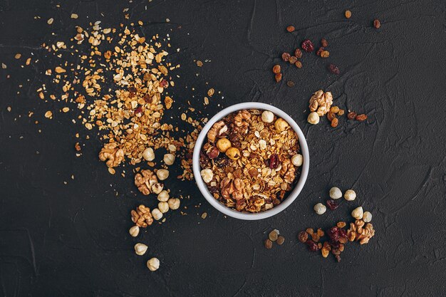 granola de farinha com nozes de mel, frutas secas e grãos é derramada do pacote em um prato