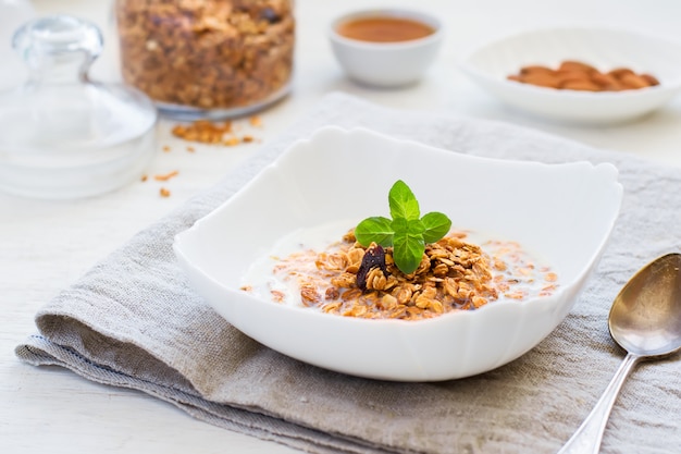 Granola con leche, miel y nueces sobre una mesa blanca