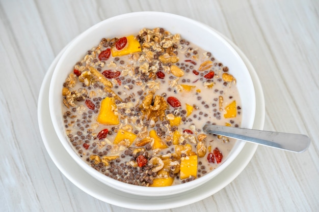 Granola con mango amarillo, bayas de goji rojas y leche de almendras, de cerca, vista superior