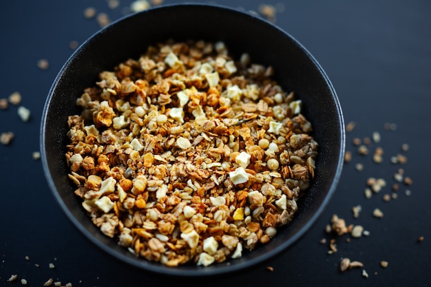 Granola de muesli afrutado casera sabrosa servida en un tazón sobre fondo oscuro. De cerca