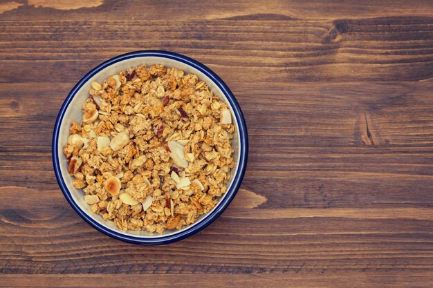 Granola con nueces en el tazón sobre superficie de madera