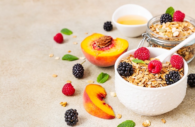 Granola ou muesli caseiro. Ingredientes para o café da manhã - granola, frutas vermelhas, pêssego, hortelã e mel.