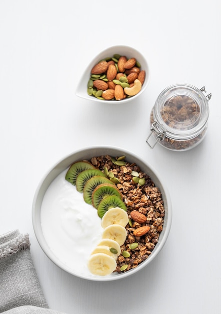 Foto granola con plátano y kiwi en una mesa blanca