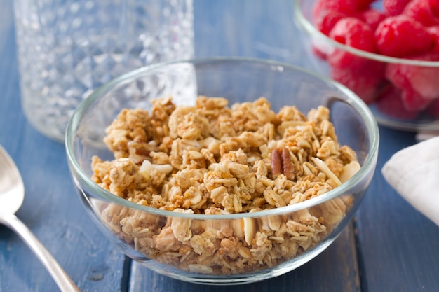 Granola en un tazón blanco con leche y frutas en madera blanca