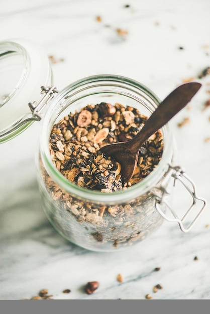 Granola de trigo sarraceno y chocolate con avellanas en primer plano de tarro de cristal