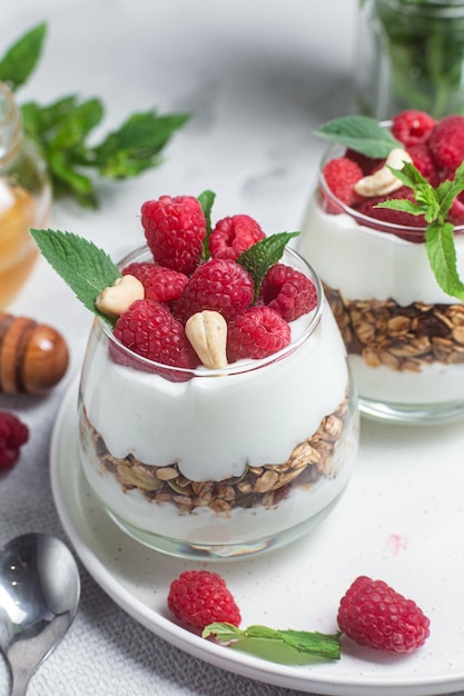 Foto granola con yogur y frambuesas en vaso
