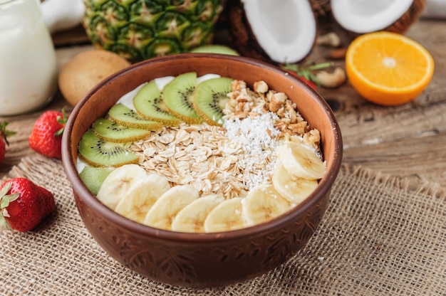 Granola con yogur griego y frutas sobre un fondo de madera en estilo rústico