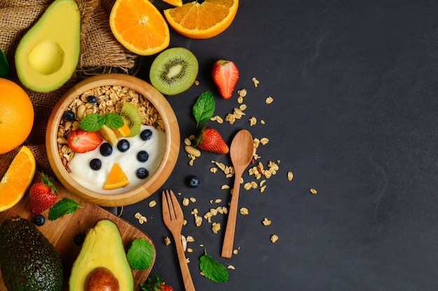 Granola y yogurt con frutas en cuenco de madera.