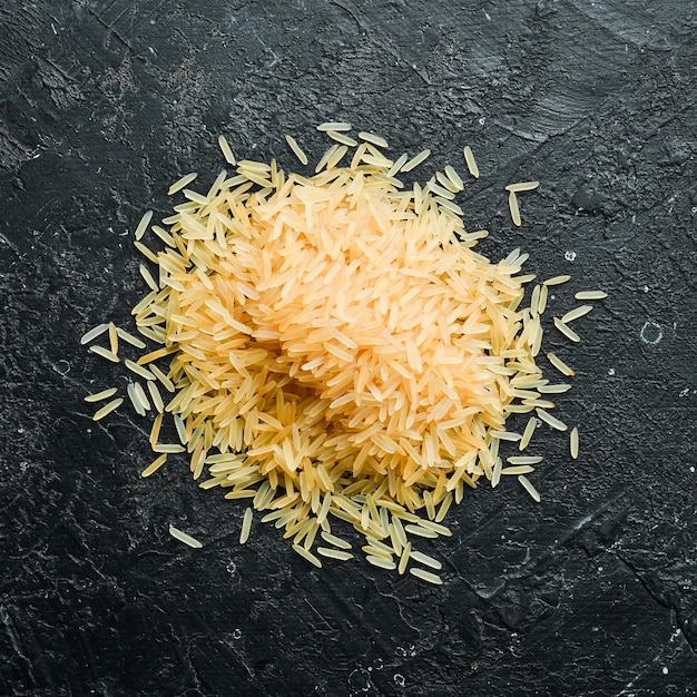 Granos de arroz en una cuchara de madera sobre un fondo de piedra Alimentos saludables