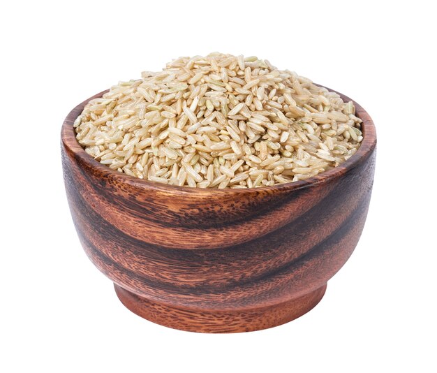 Granos de arroz integral en un tazón de madera aislado en blanco
