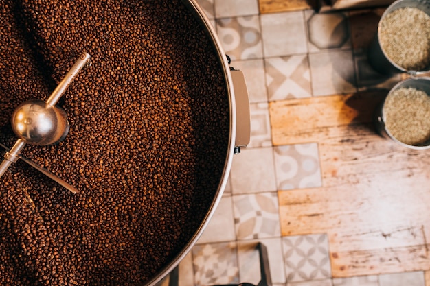 Granos de café aromáticos recién tostados sobre una moderna máquina tostadora de café. Vista desde arriba