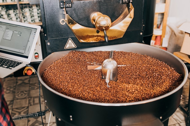 Granos de café aromáticos recién tostados sobre una moderna máquina tostadora de café.