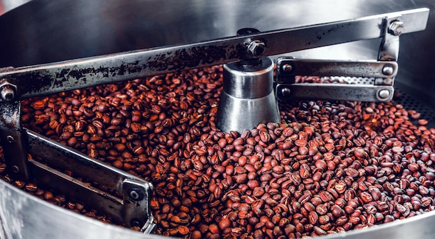 Granos de café aromáticos recién tostados sobre una moderna máquina tostadora de café