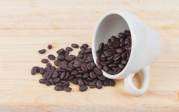 granos de café en blanco taza en la mesa de madera