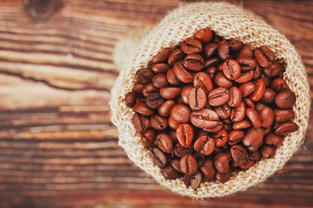 Granos de café en una bolsa de arpillera sobre una superficie de madera Contraste suave Granos de café tostados aromáticos