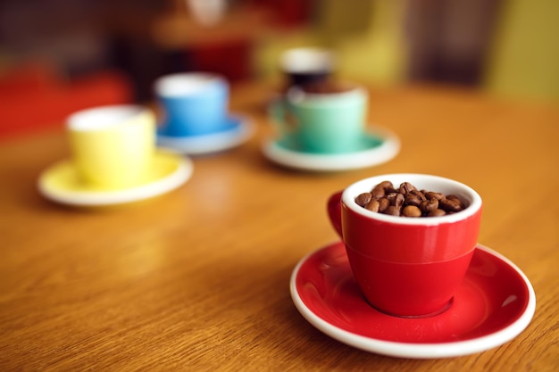 Granos de café en bolsa y cuchara con taza de café roja sobre mesa de madera blackground borroso