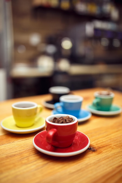 Granos de café en bolsa y cuchara con taza de café roja sobre mesa de madera blackground borroso